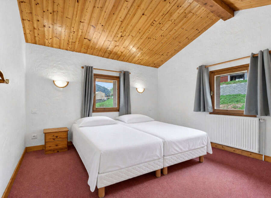 Discover the charm of this cozy bedroom featuring a unique wooden ceiling and a comfortable twin bed setup.