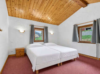 Discover the charm of this cozy bedroom featuring a unique wooden ceiling and a comfortable twin bed setup.