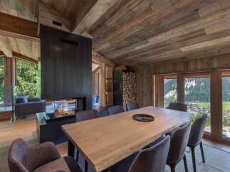 Experience luxury living in this stunning chalet featuring a modern fireplace and a spacious dining area.