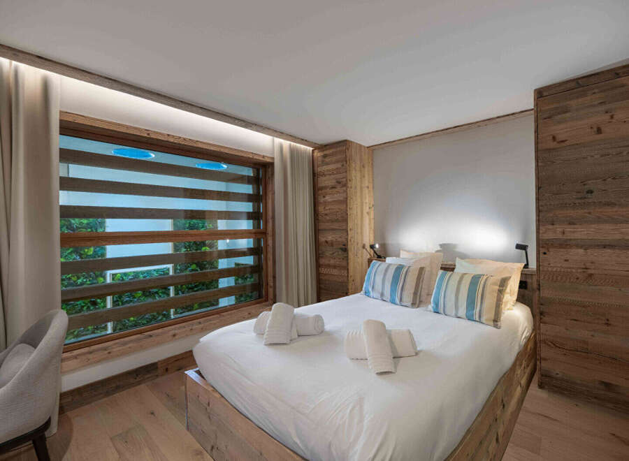 Experience luxury in this stunning bedroom featuring a cozy bed, stylish pillows, and a unique window design.