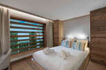 Experience luxury in this stunning bedroom featuring a cozy bed, stylish pillows, and a unique window design.