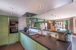 This modern kitchen boasts sleek, green cabinetry and a dark countertop, creating a stylish and functional space.