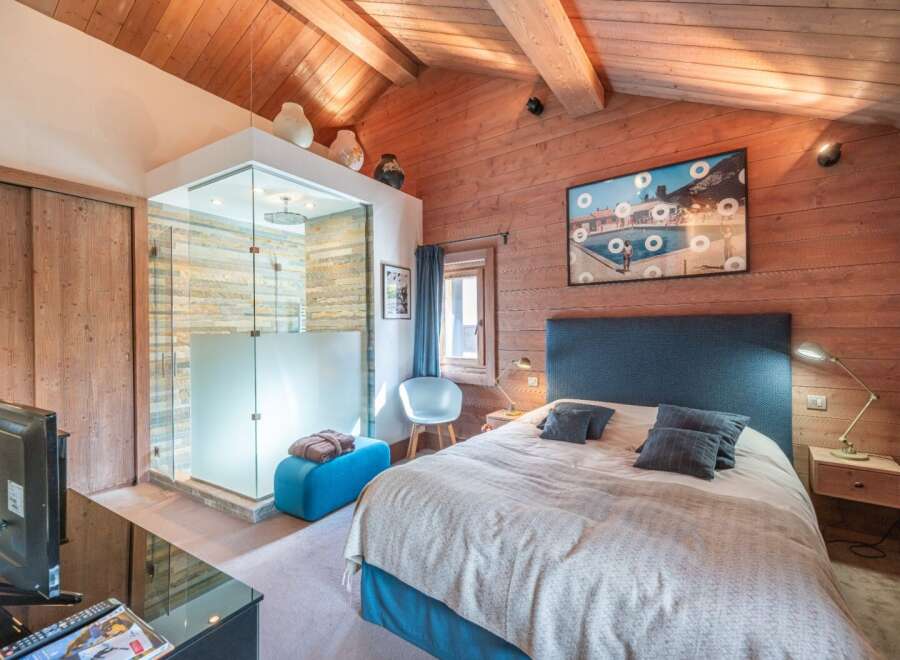 Experience luxury in this stunning bedroom featuring a modern glass shower and a cozy seating area.