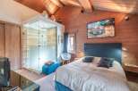 Experience luxury in this stunning bedroom featuring a modern glass shower and a cozy seating area.