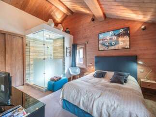 Experience luxury in this stunning bedroom featuring a modern glass shower and a cozy seating area.