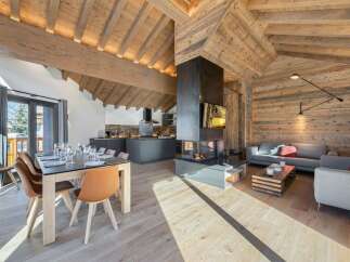 Experience luxury living in this stunning chalet, featuring a modern kitchen and a cozy living area with a fireplace.