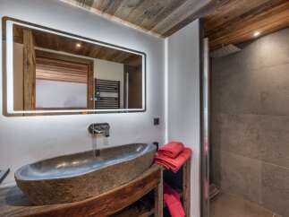 Experience luxury in this stunning bathroom featuring a unique stone sink and a modern, illuminated mirror.