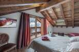Experience the charm of this cozy bedroom featuring a rustic wooden ceiling and a private balcony with stunning mountain views.