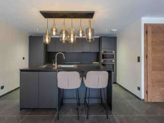 This modern kitchen boasts sleek, dark cabinetry and a stylish island with seating, perfect for entertaining.