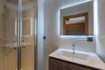 Step into a modern bathroom oasis! This stunning space features a sleek glass shower enclosure, a stylish vanity with a contemporary sink, and a large mirror with integrated lighting.