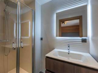Step into a modern bathroom oasis! This stunning space features a sleek glass shower enclosure, a stylish vanity with a contemporary sink, and a large mirror with integrated lighting.