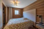This cozy bedroom features a warm wooden accent wall and a comfortable bed with a plush, patterned comforter.