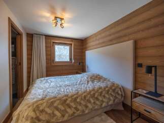 This cozy bedroom features a warm wooden accent wall and a comfortable bed with a plush, patterned comforter.