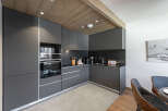This modern kitchen features sleek, dark gray cabinetry and a built-in oven, creating a stylish and functional space.