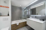 This modern bathroom features a sleek design with gray tiled walls and a white vanity.