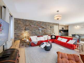 Experience luxury living in this stunning property, featuring a spacious living area with a vibrant red sofa and a cozy fireplace.