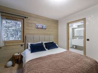 Experience the charm of this cozy bedroom featuring a rustic wooden accent wall and a comfortable bed.