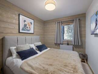 This cozy bedroom features rustic wood paneling and a comfortable bed, creating a warm and inviting atmosphere.