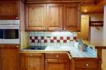 This charming kitchen boasts warm wooden cabinetry and a classic tiled backsplash, creating a cozy and inviting atmosphere.