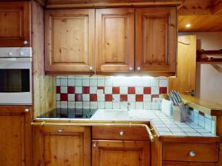 This charming kitchen boasts warm wooden cabinetry and a classic tiled backsplash, creating a cozy and inviting atmosphere.