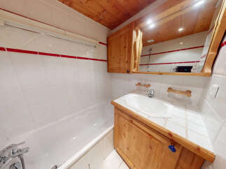 This charming bathroom features a classic design with wooden cabinetry and a bright, clean aesthetic.