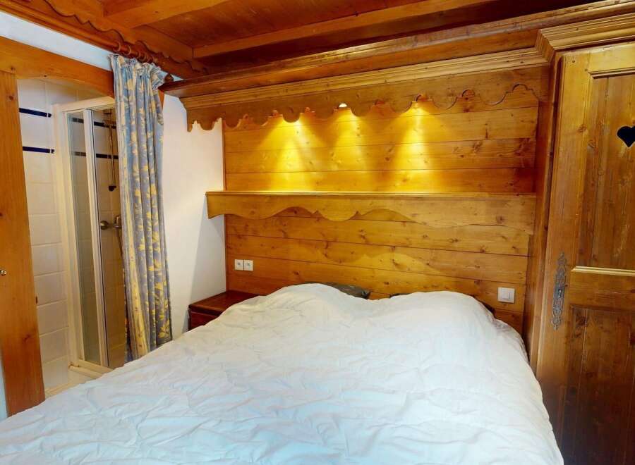 Discover the charm of this cozy bedroom featuring a rustic wooden headboard and a comfortable bed.