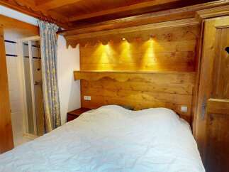 Discover the charm of this cozy bedroom featuring a rustic wooden headboard and a comfortable bed.