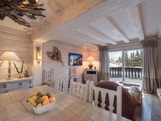 Experience rustic charm in this mountain retreat, featuring a cozy dining area with a wooden table laden with fresh fruit.