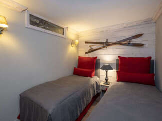 This charming bedroom features two twin beds with plush red pillows, perfect for a cozy retreat.