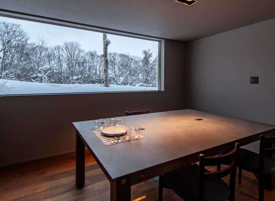 Experience the tranquility of this stunning property, featuring a dining room with a breathtaking view of a snow-covered landscape.
