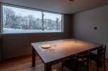 Experience the tranquility of this stunning property, featuring a dining room with a breathtaking view of a snow-covered landscape.