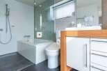 Step into luxury with this modern bathroom, featuring a sleek glass-enclosed shower and a relaxing bathtub.