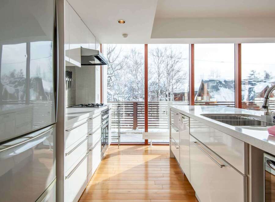 This modern kitchen boasts sleek white cabinetry and countertops, creating a bright and airy atmosphere.