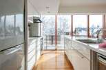 This modern kitchen boasts sleek white cabinetry and countertops, creating a bright and airy atmosphere.