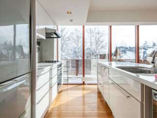 This modern kitchen boasts sleek white cabinetry and countertops, creating a bright and airy atmosphere.