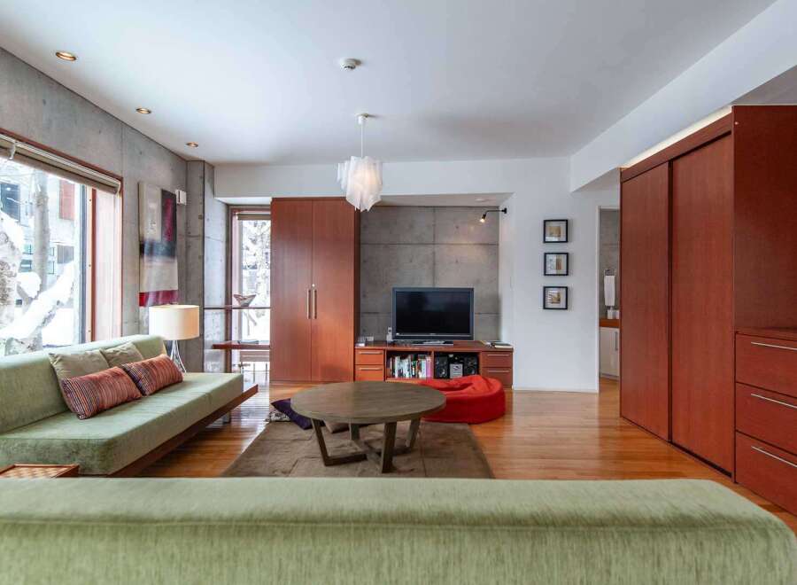 This modern living space boasts a sleek design with concrete walls and warm wooden accents.