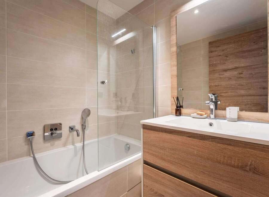 This modern bathroom features a sleek design with a glass shower enclosure and a stylish wooden vanity.