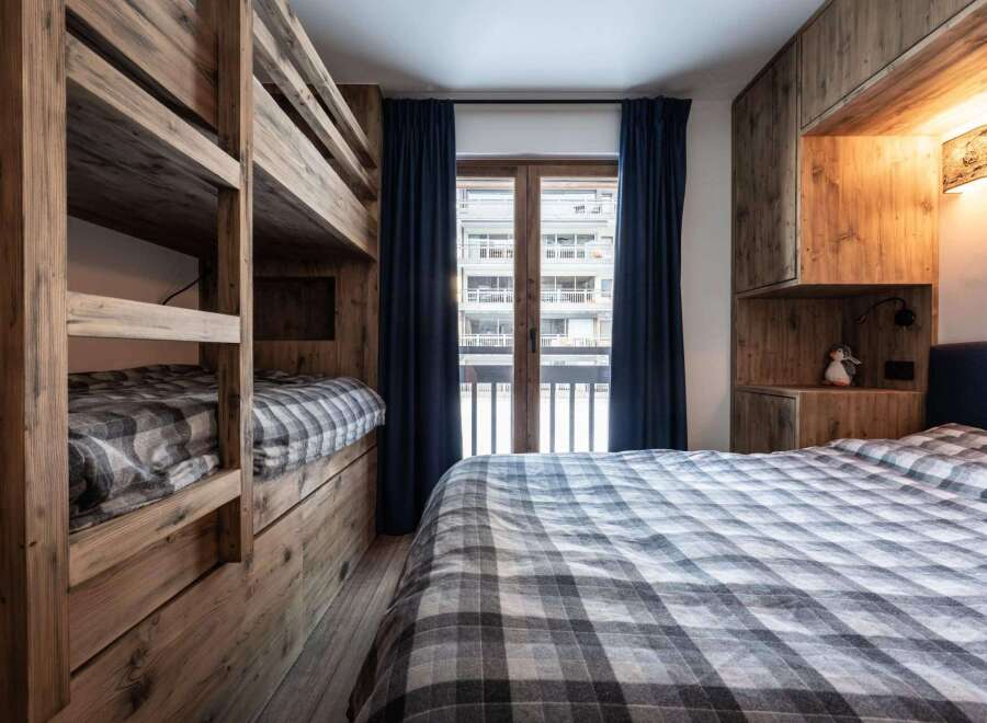This cozy bedroom features custom-built wooden bunk beds, perfect for accommodating guests or family.
