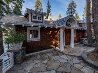Nestled amidst towering trees, this charming property boasts a unique architectural design with a shingle exterior and inviting stone pathway.