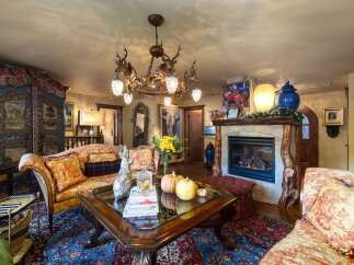 Step into luxury with this stunning living room, featuring a unique antler chandelier and a cozy fireplace.