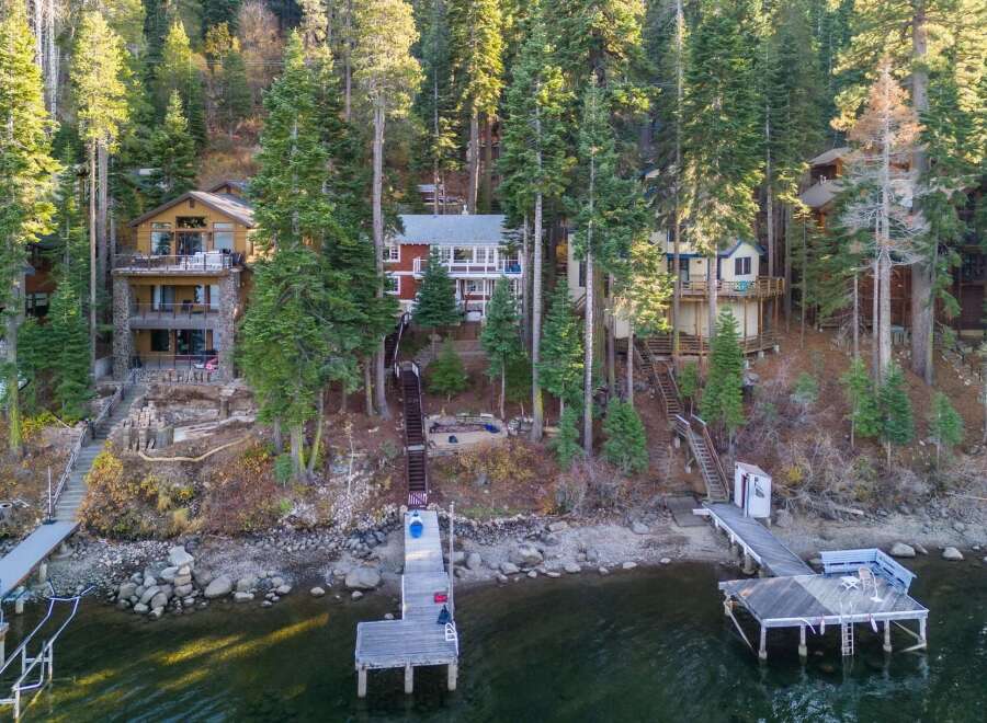 Discover your dream lakeside retreat! This stunning property boasts multiple homes nestled amongst towering trees, offering unparalleled privacy and breathtaking views.