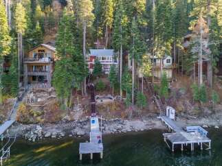 Discover your dream lakeside retreat! This stunning property boasts multiple homes nestled amongst towering trees, offering unparalleled privacy and breathtaking views.