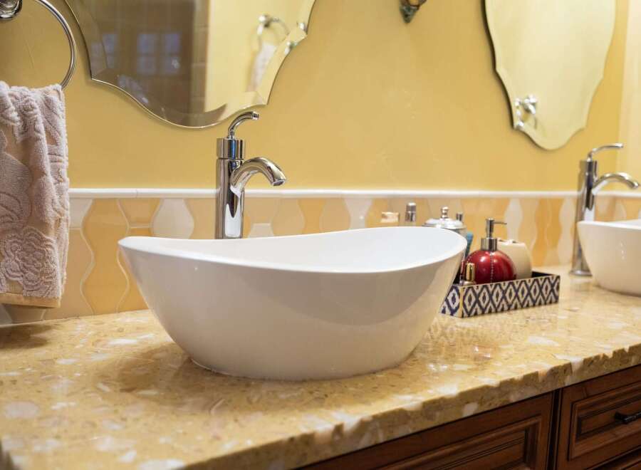This stunning bathroom boasts a modern design with a sleek, white vessel sink and elegant chrome fixtures.