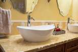 This stunning bathroom boasts a modern design with a sleek, white vessel sink and elegant chrome fixtures.