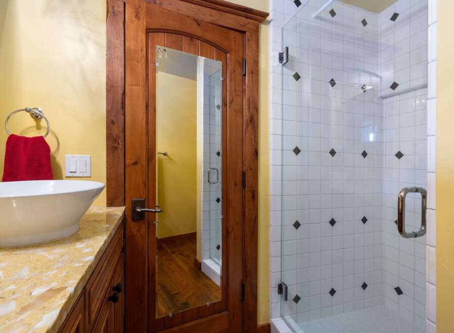 Step into luxury with this stunning bathroom featuring a custom wooden door with a built-in mirror.