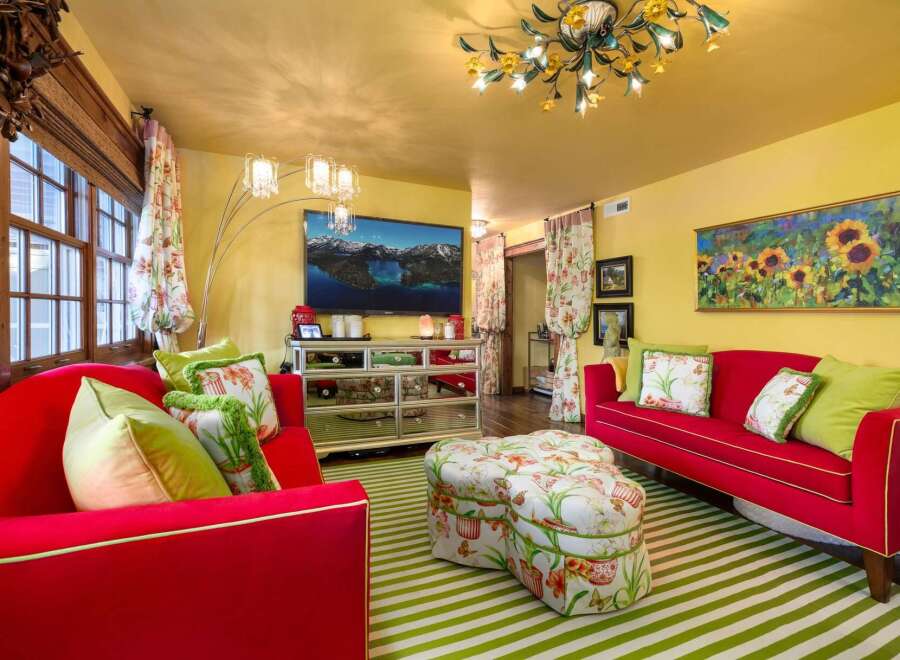 Step into a vibrant living space with this stunning property, featuring a bold red sofa and a matching ottoman, creating a focal point of style.