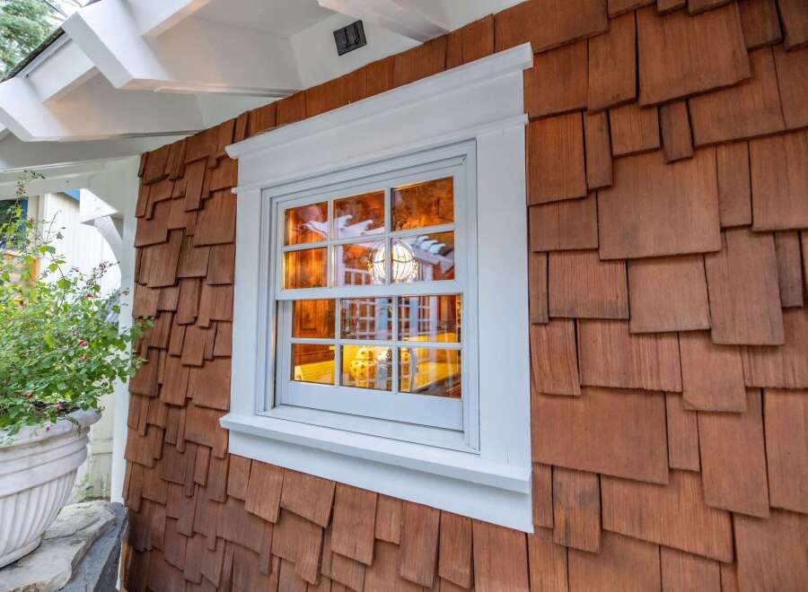 This charming property boasts a unique architectural design, featuring a beautiful window with a white frame and a warm, inviting interior.