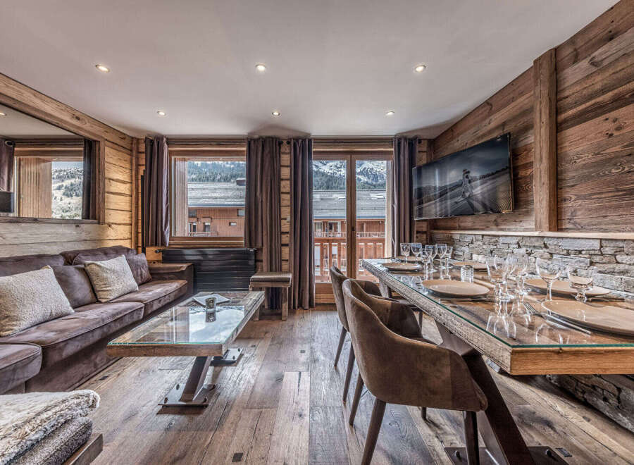 Experience luxurious mountain living in this stunning chalet, featuring a spacious living area with a plush sofa and a modern glass-top dining table set for a feast.
