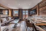 Experience luxurious mountain living in this stunning chalet, featuring a spacious living area with a plush sofa and a modern glass-top dining table set for a feast.