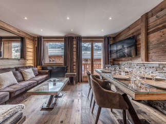 Experience luxurious mountain living in this stunning chalet, featuring a spacious living area with a plush sofa and a modern glass-top dining table set for a feast.